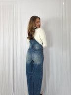 Person wearing blue denim overalls against a white background
