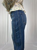 Person wearing blue jeans and a floral top against a white background