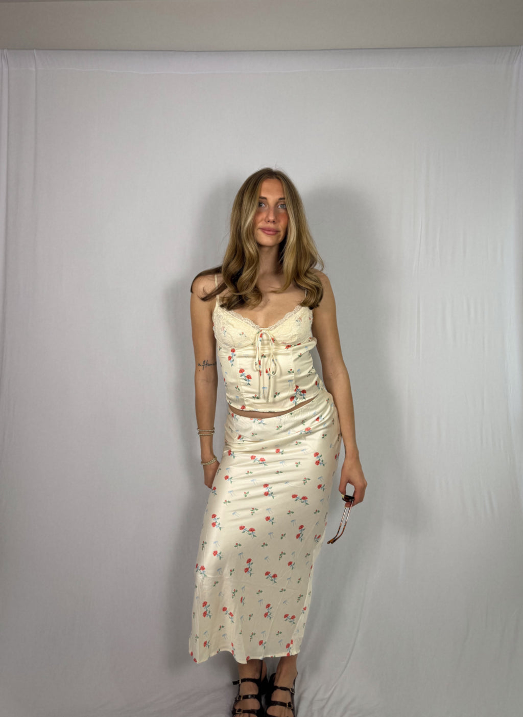Woman wearing a floral skirt set against a plain white background