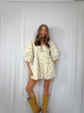 Woman wearing a polka dot romper and yellow boots against a white background