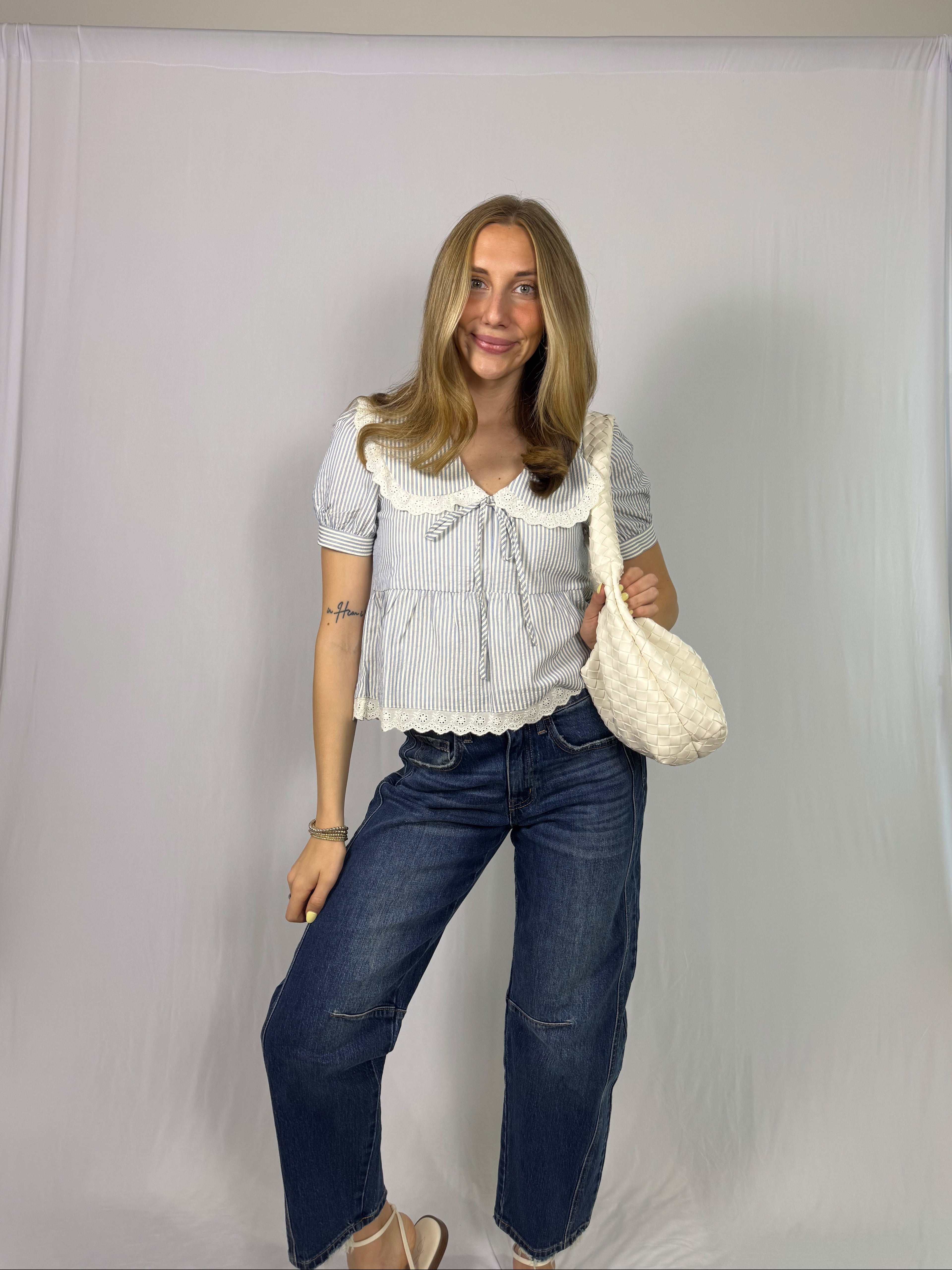 Woman holding a white bag against a plain background