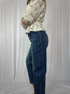 Person wearing a floral blouse and blue jeans against a plain background