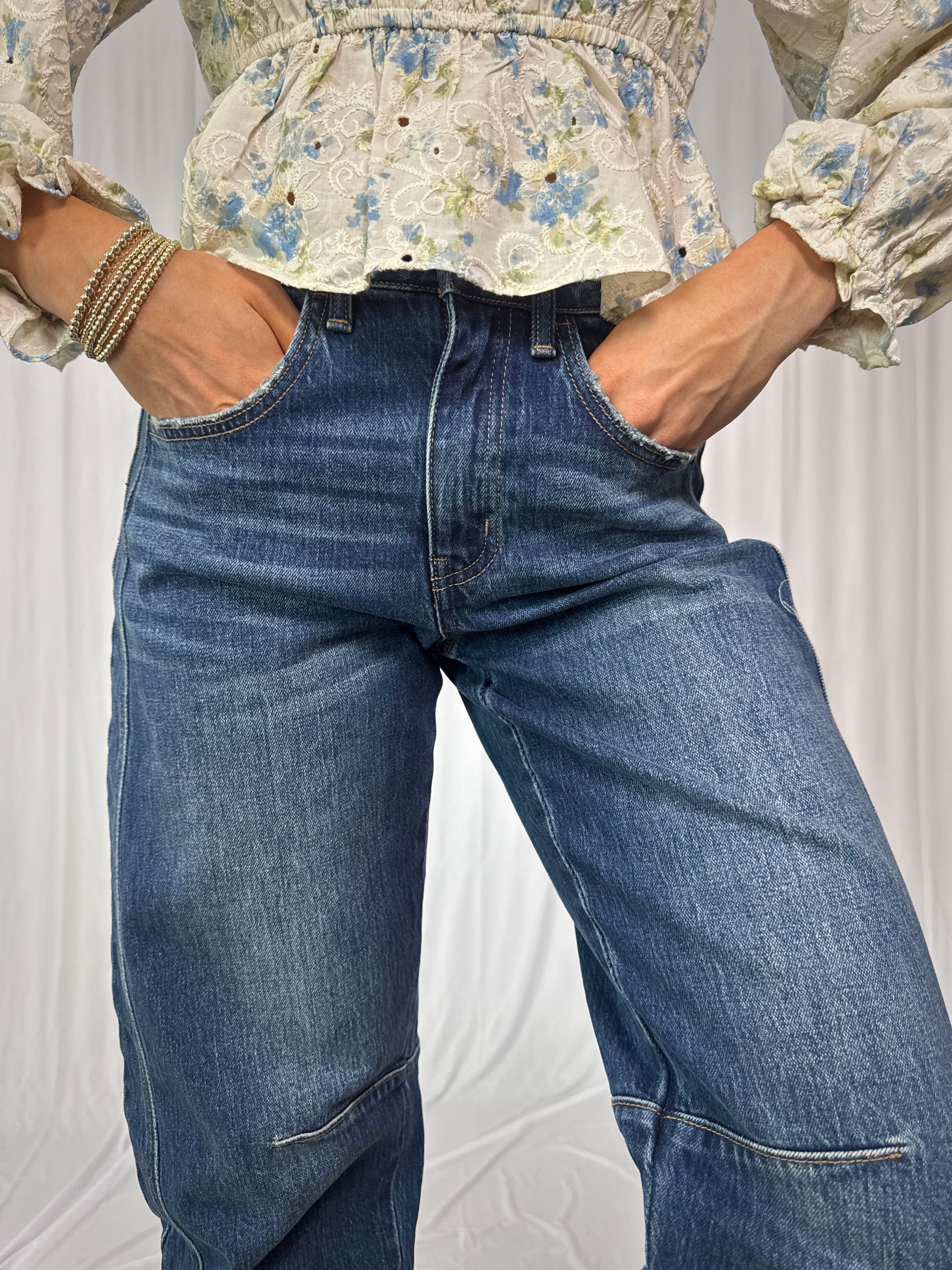 Person wearing a floral blouse and blue jeans against a white background
