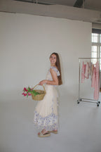 Woman holding a basket with flowers in a minimalistic room.