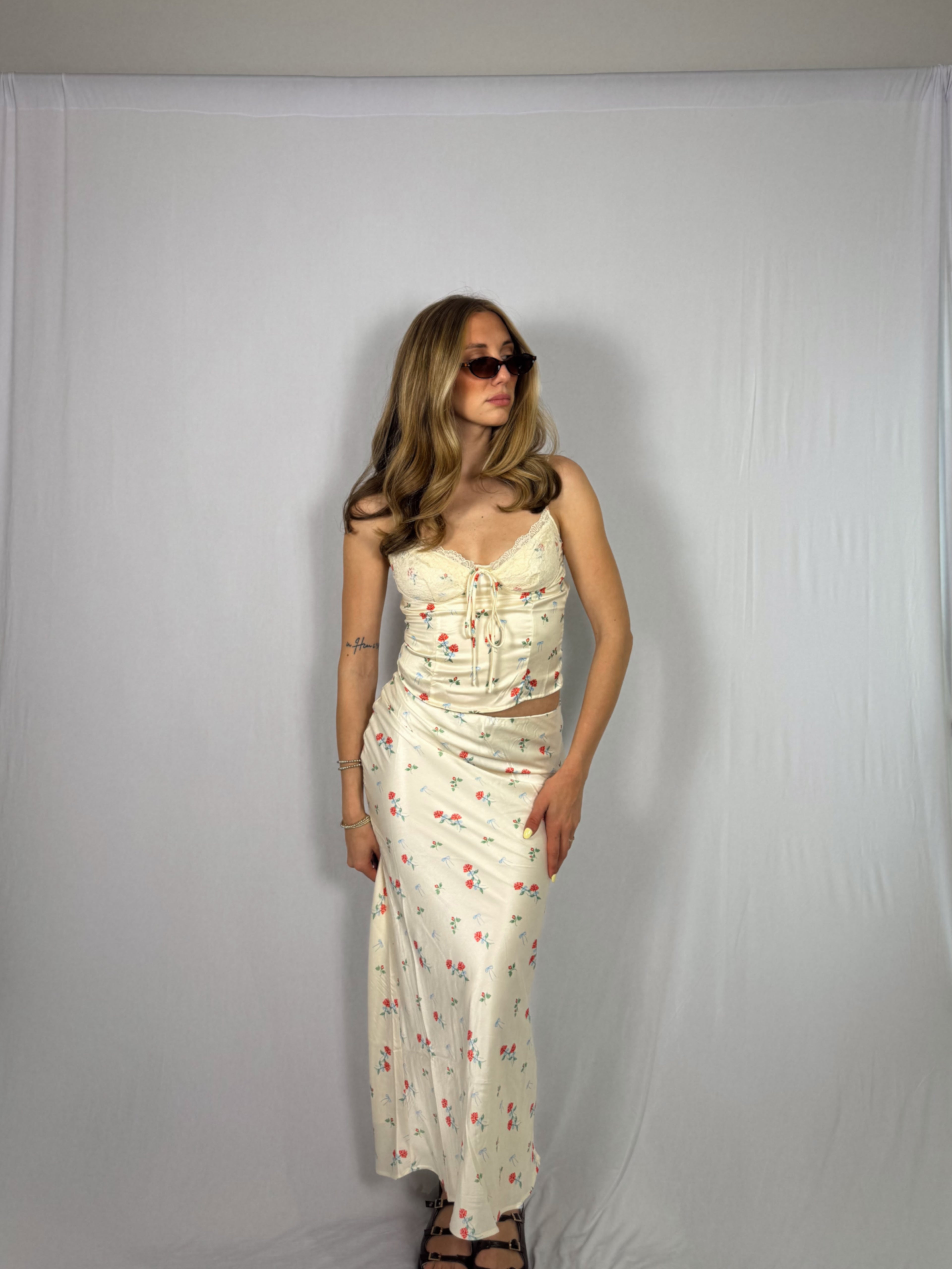Woman wearing a floral skirt set against a plain background