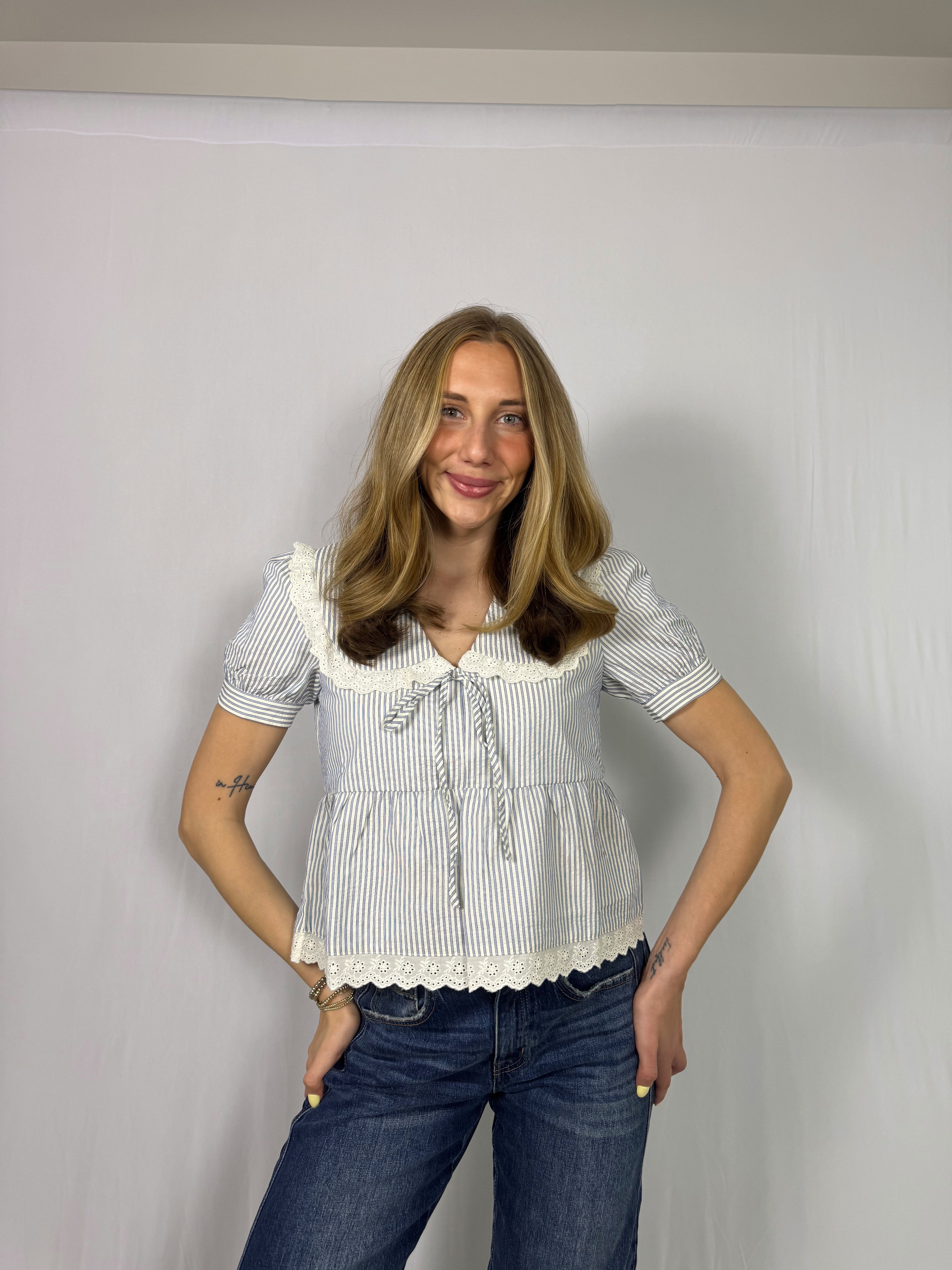 Woman wearing a white and blue striped blouse with a plain background