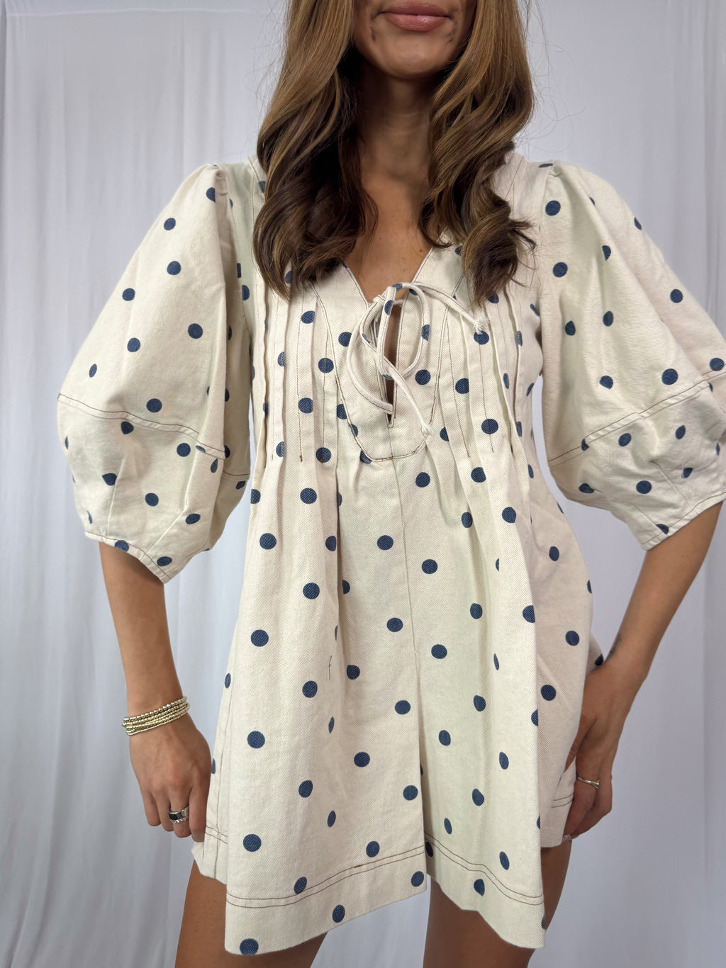 Woman wearing a polka dot romper against a plain background