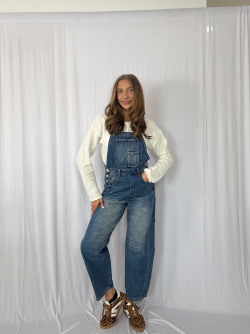 Person wearing blue denim overalls against a white background