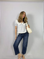 Woman wearing a striped blouse and blue jeans against a plain white background