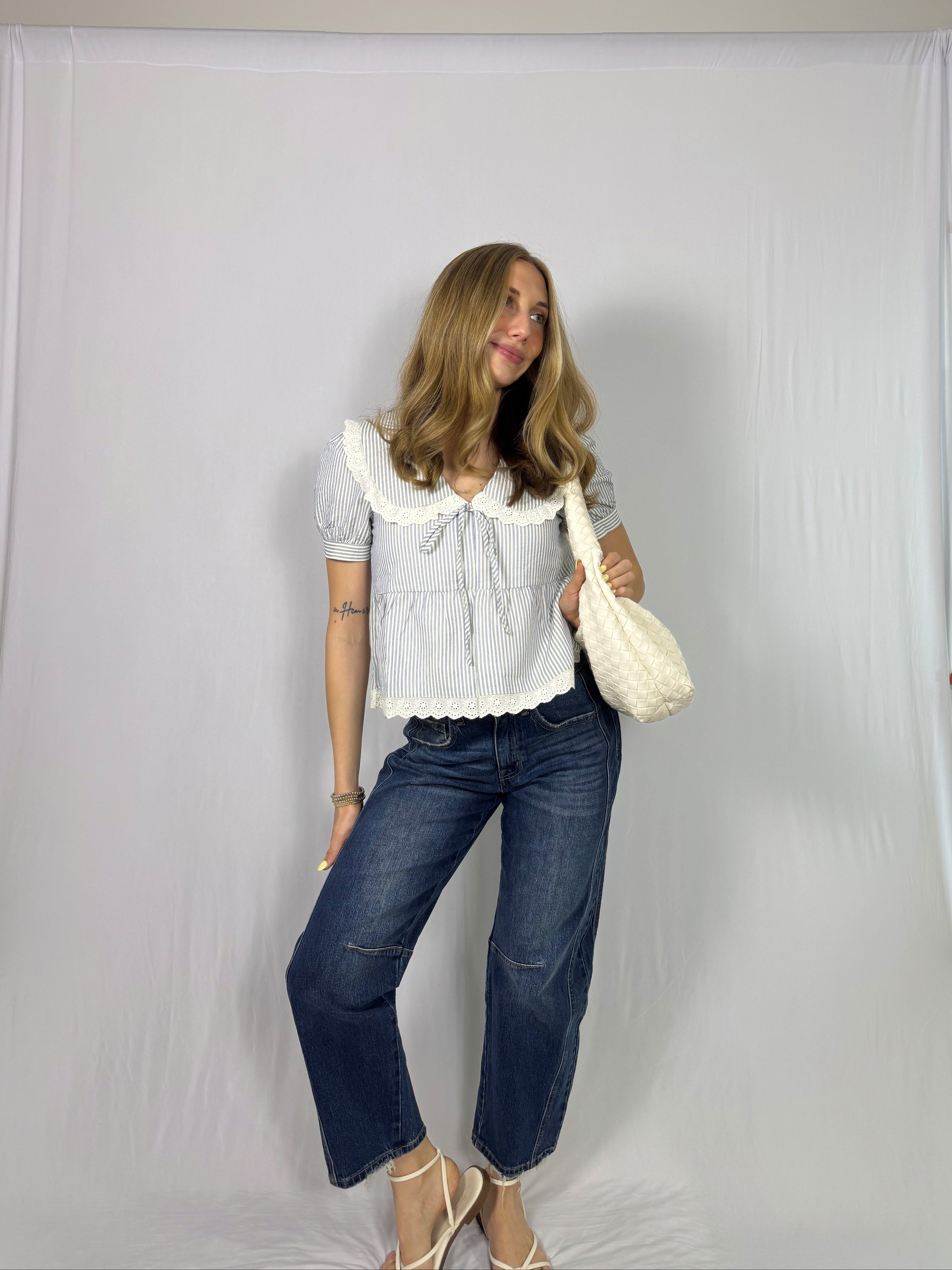 Woman wearing a striped blouse and blue jeans against a plain white background