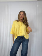 Woman wearing a yellow sweater and blue jeans against a white background