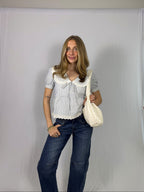 Woman holding a white bag against a plain background