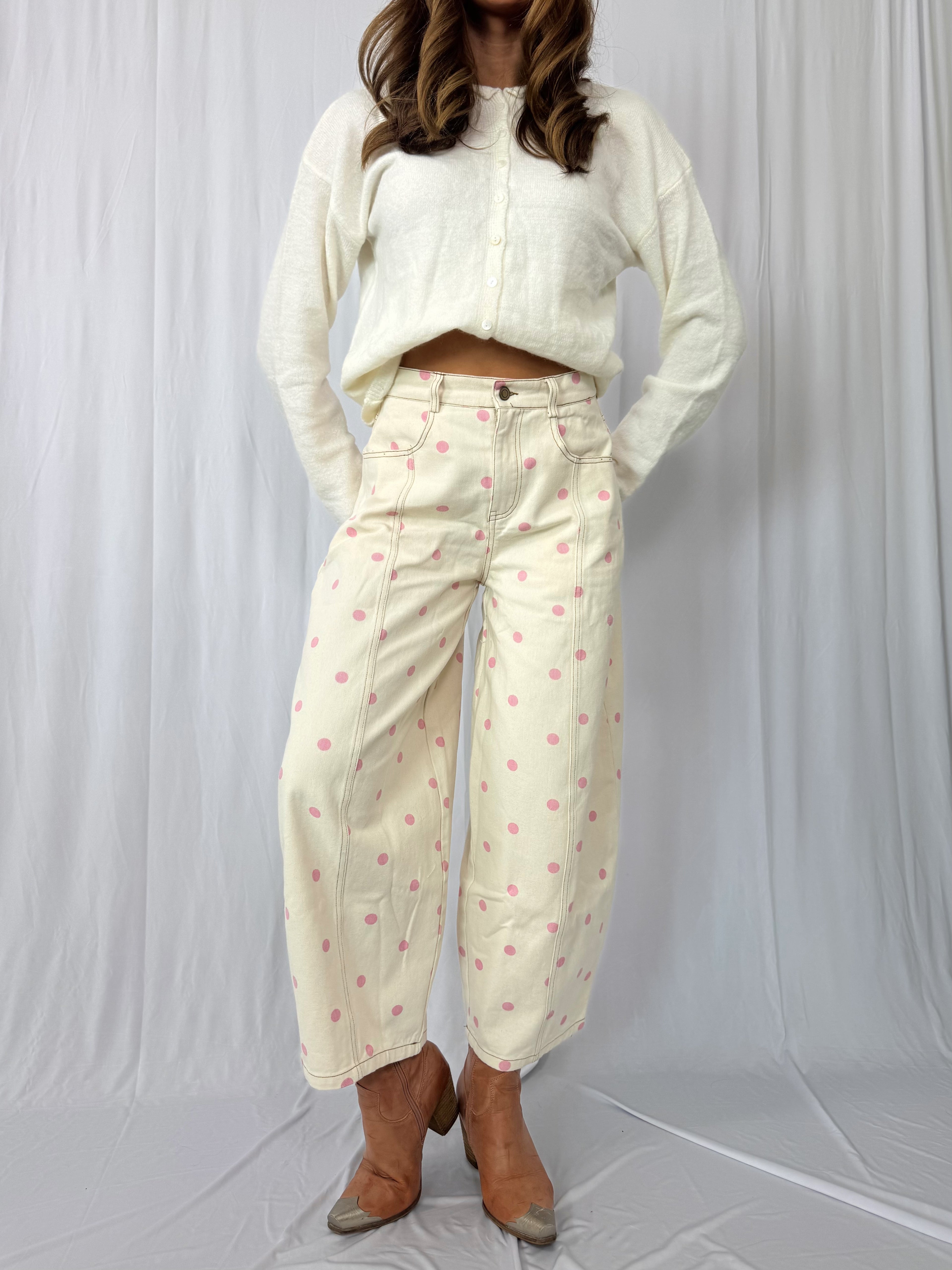 Person wearing a white outfit with patterned pants on a plain background