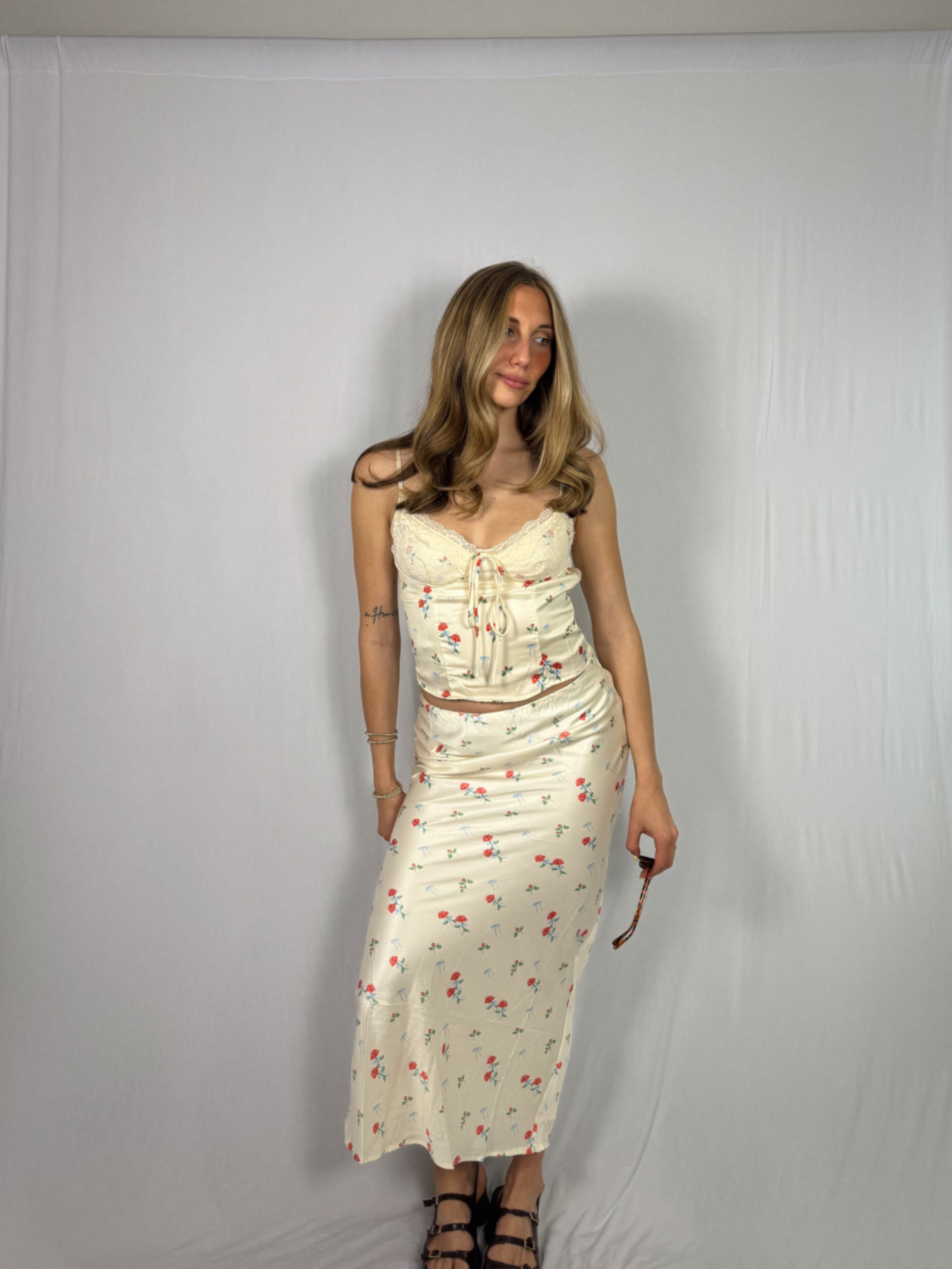 Woman wearing a floral skirt set against a plain background