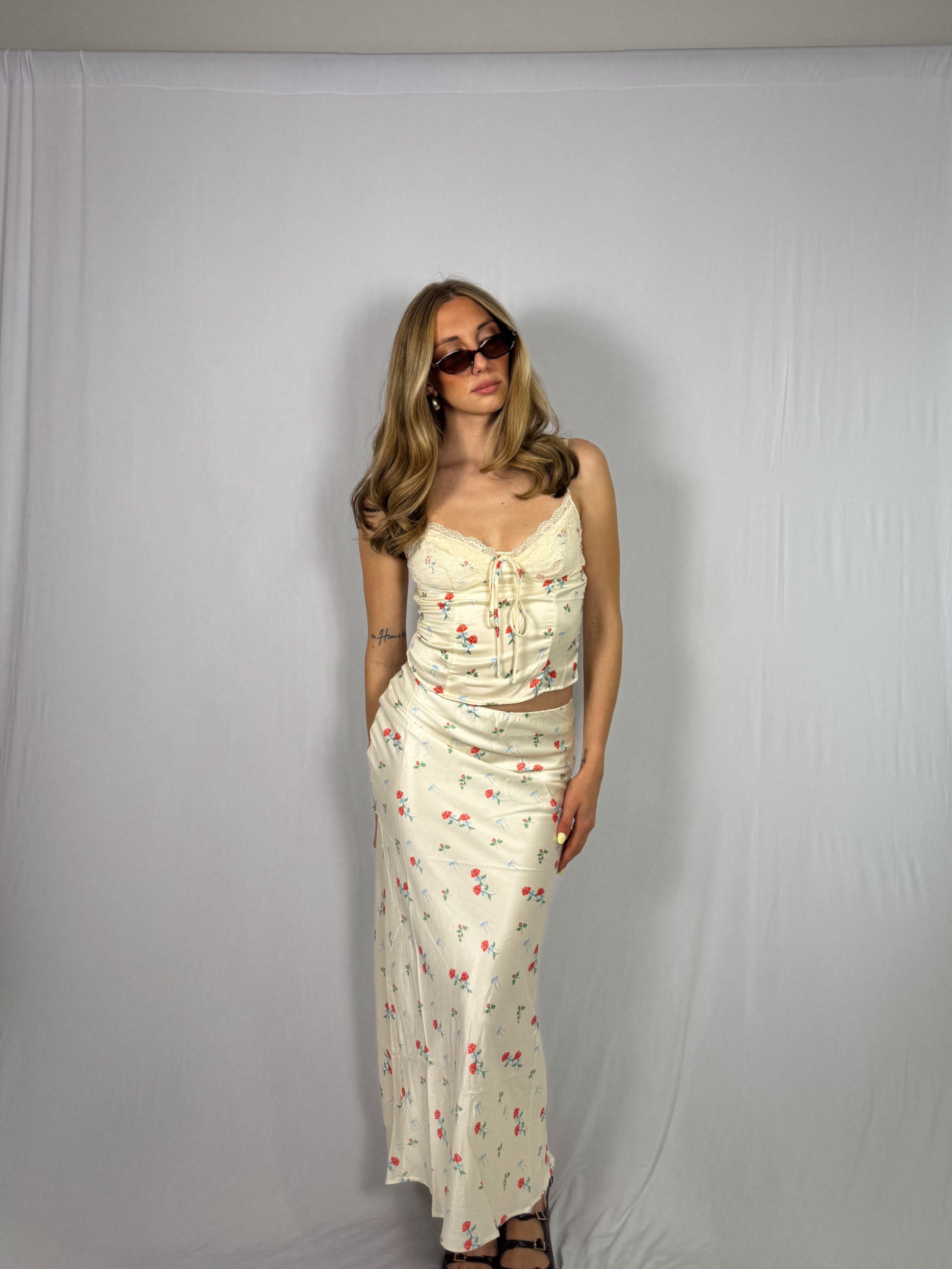 Woman wearing a floral skirt set against a plain white background