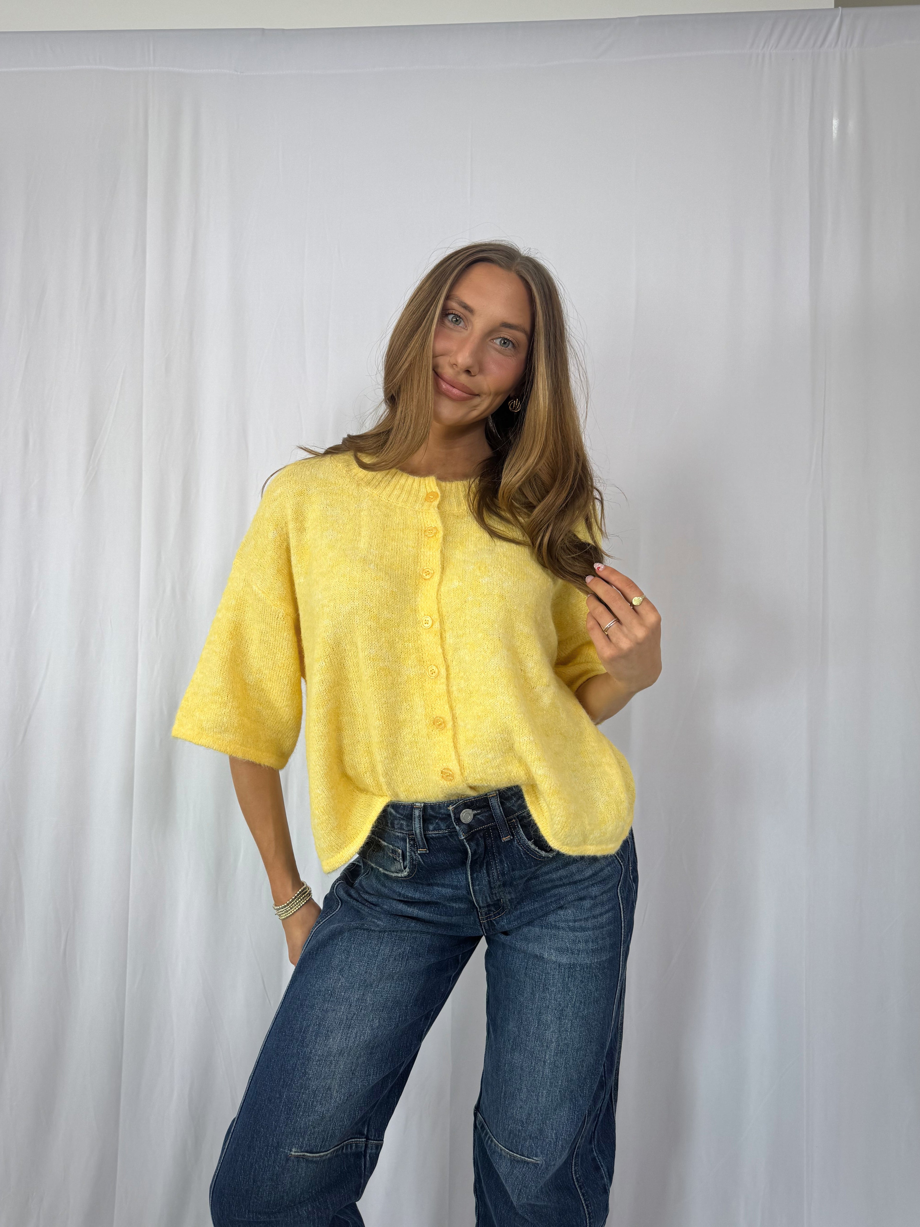 Woman wearing a yellow shirt and blue jeans against a white background