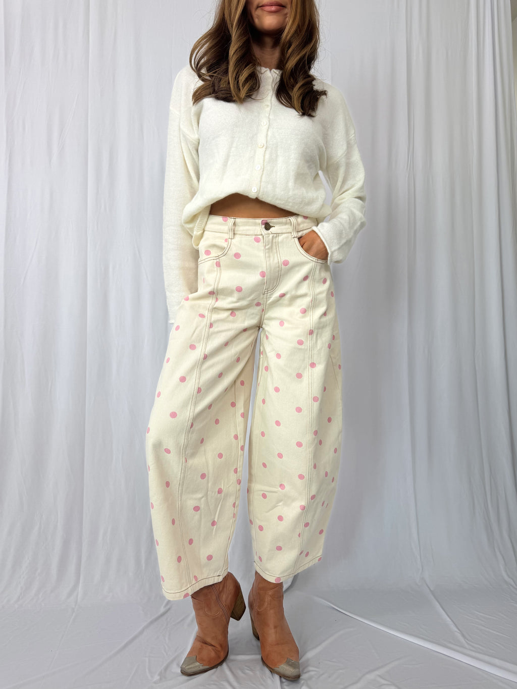 Woman wearing a white long-sleeve top and patterned pants on a white background