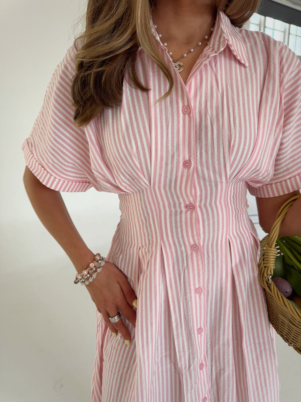 Woman wearing a pink and white striped dress holding a basket.