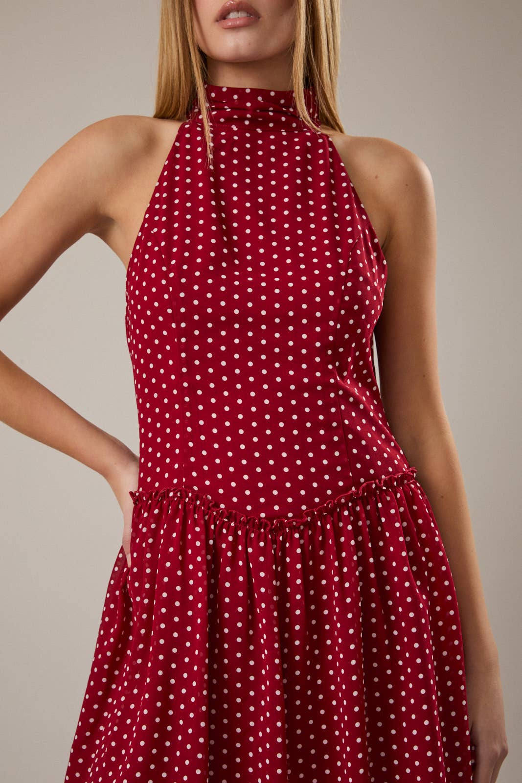 Red polka dot dress worn by a model on a neutral background