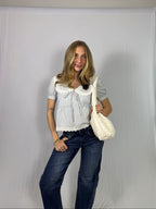 Woman holding a white bag against a plain background