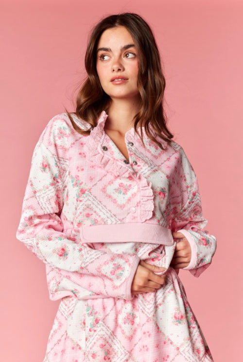 Woman wearing a pink floral outfit against a pink background