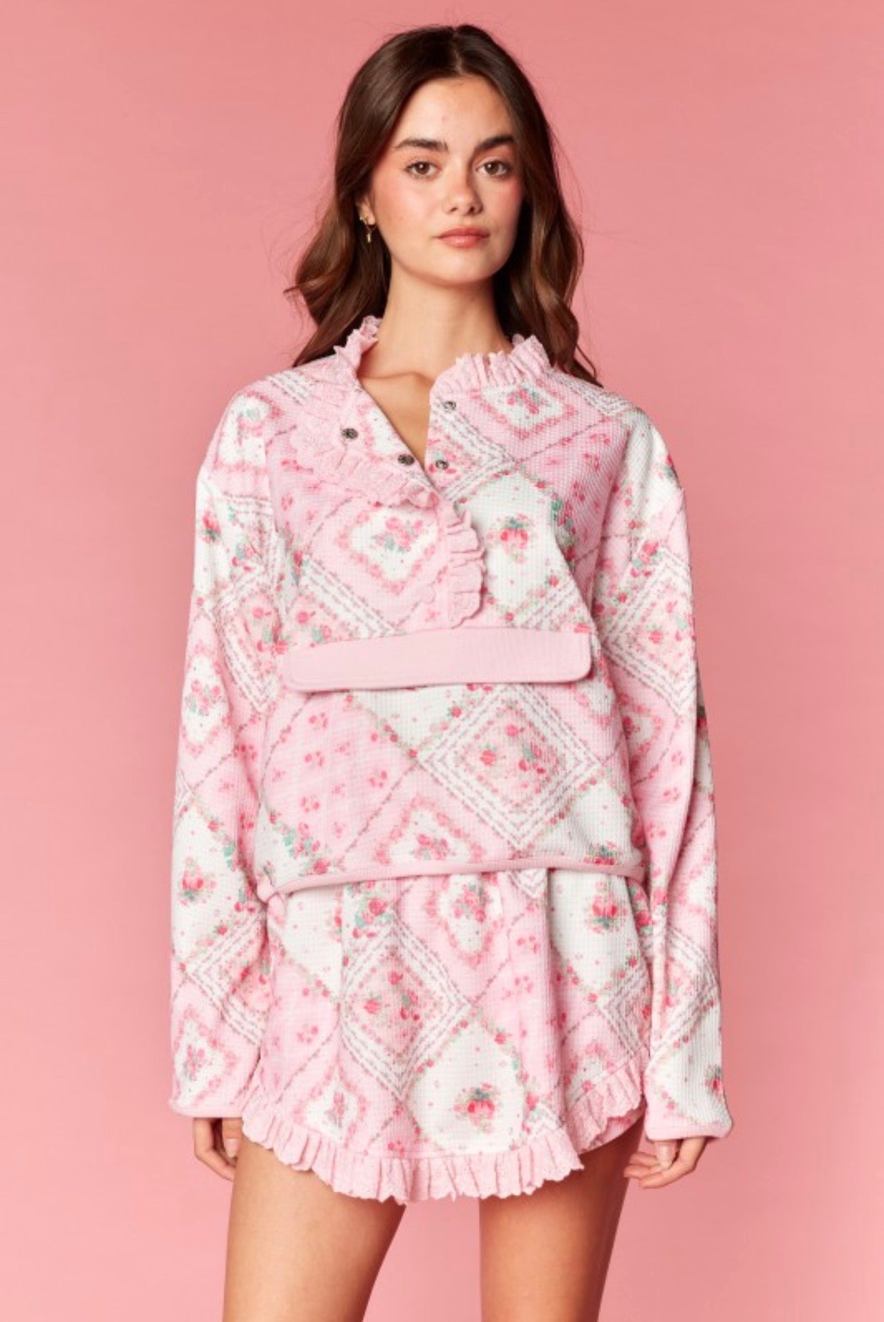 Woman wearing a pink floral skort set against a pink background