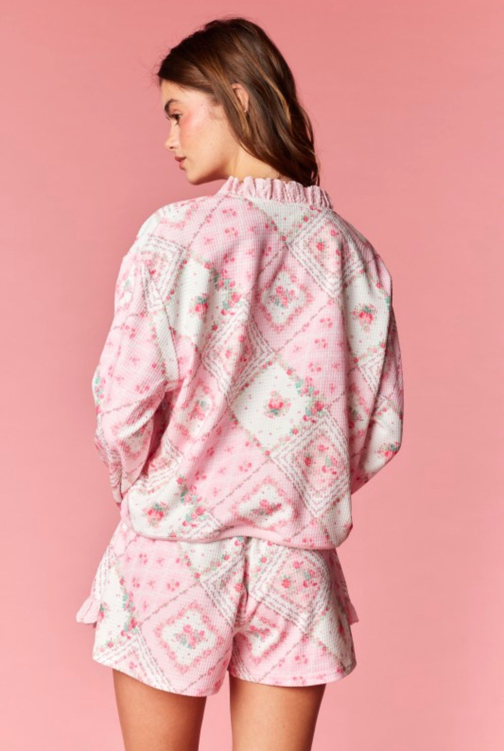 Woman wearing a pink floral skort set against a pink background