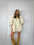 Woman wearing a polka dot romper and yellow boots against a white background