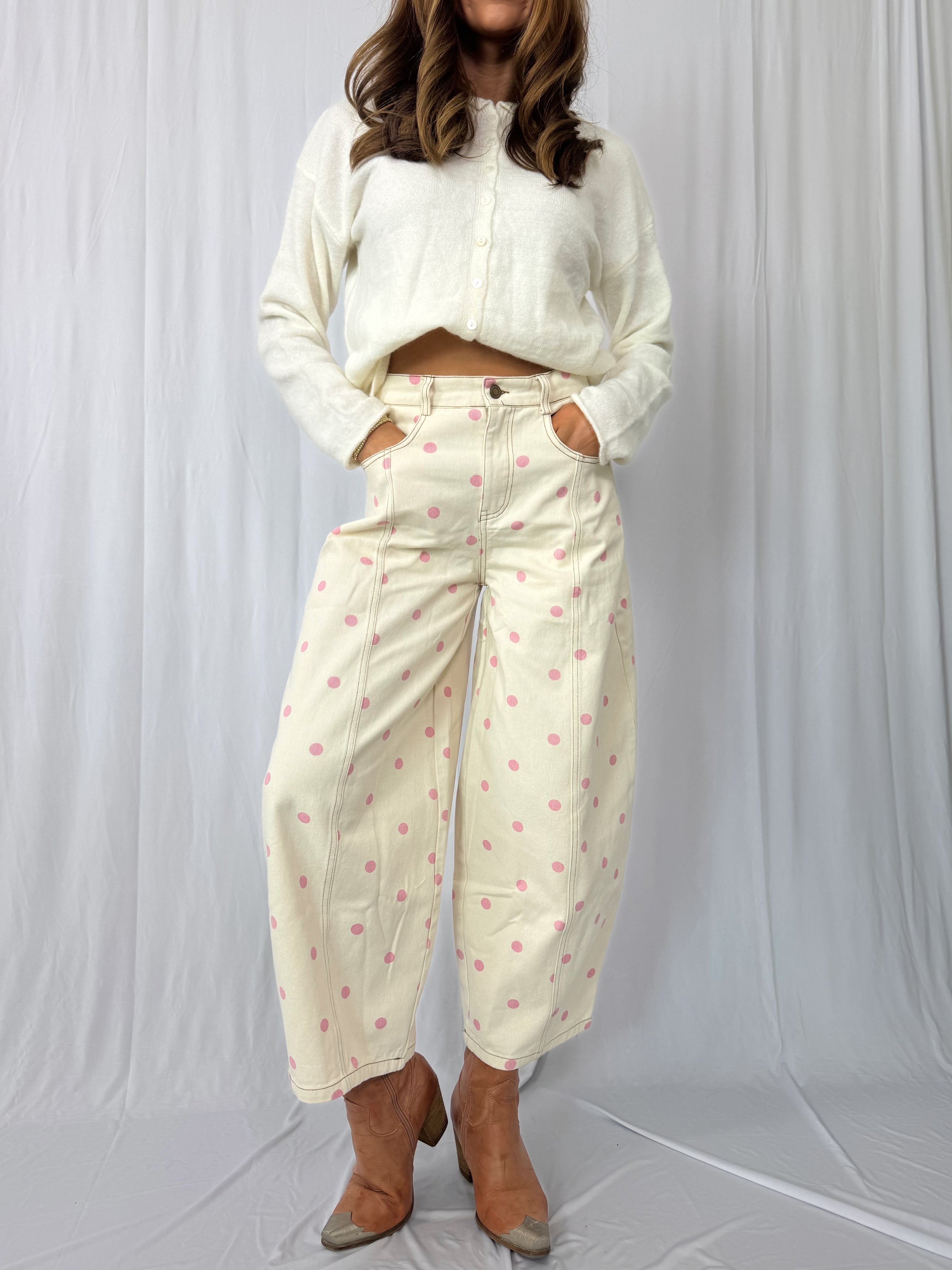 Person wearing a white cropped jacket and cream pants with pink polka dots against a white background