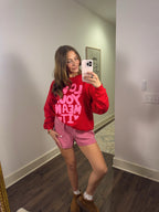 Person wearing a red sweatshirt and pink checkered shorts taking a mirror selfie.