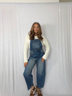 Woman wearing blue denim overalls against a white background
