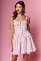 Woman wearing a pink floral dress against a pink background