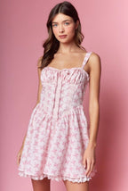Woman wearing a pink floral dress against a pink background