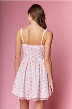 Woman wearing a pink floral dress against a pink background