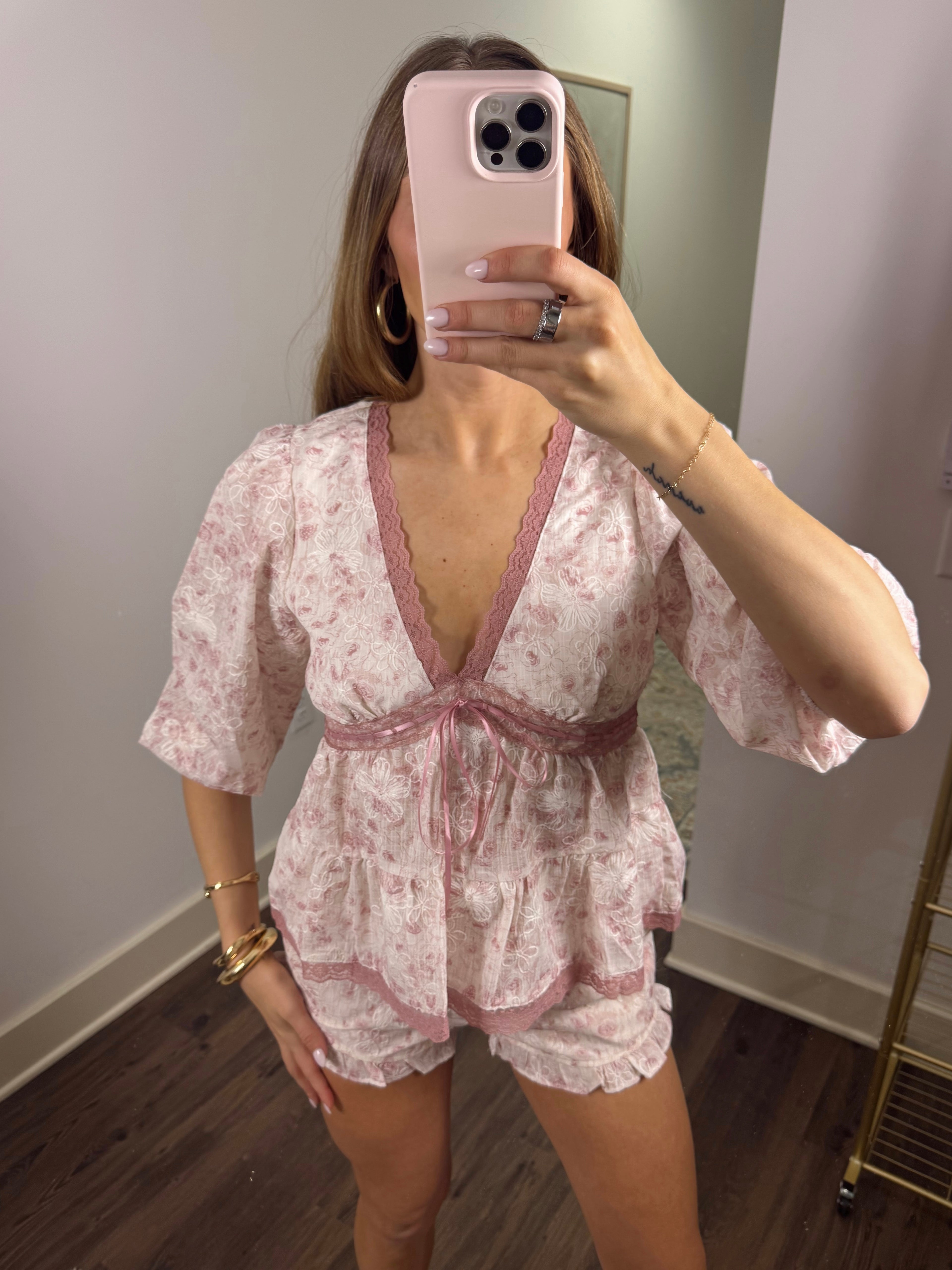 Woman taking a mirror selfie wearing a floral romper.