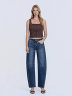 Woman wearing a brown top and blue jeans on a white background