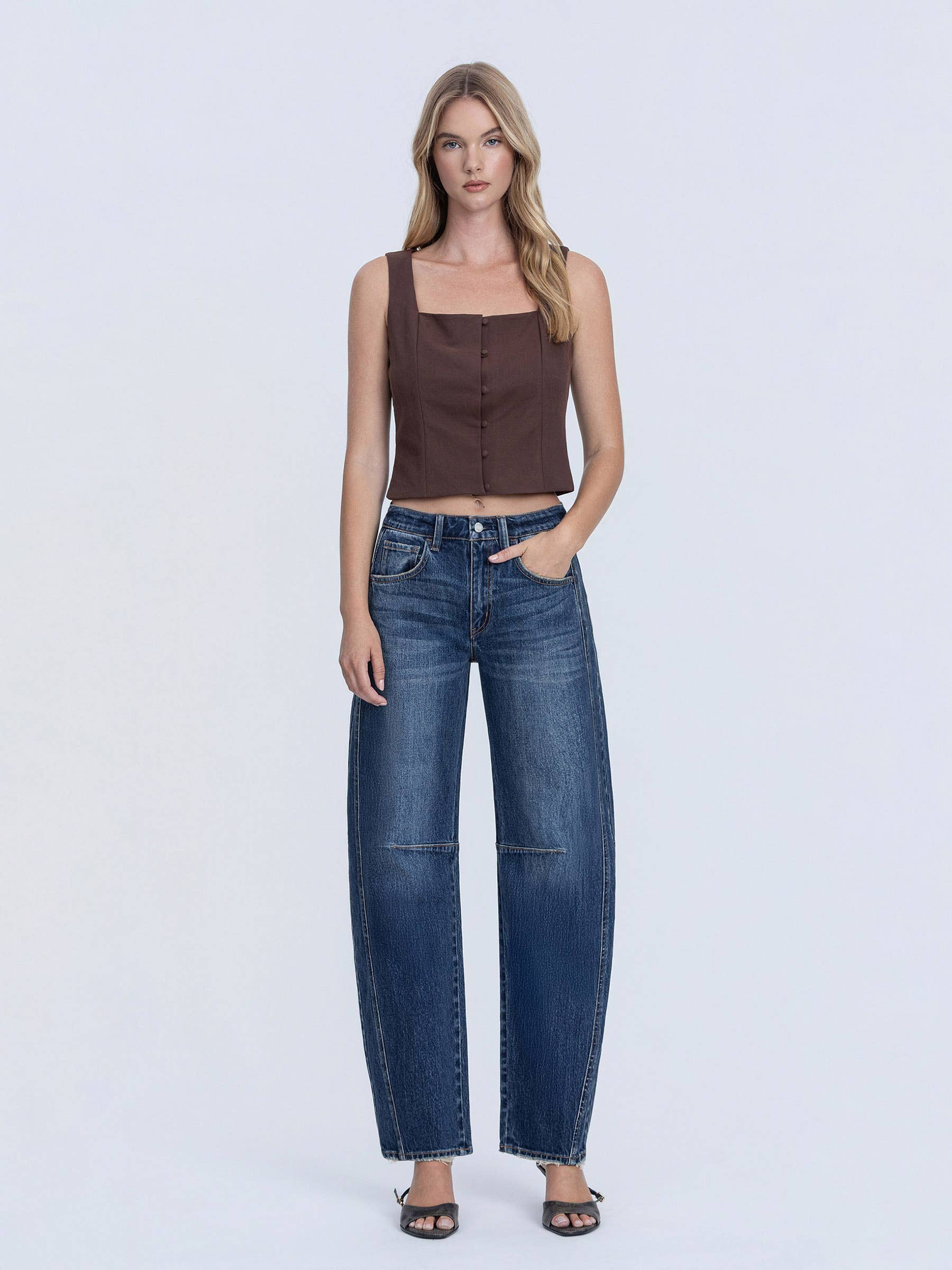 Woman wearing a brown top and blue jeans on a white background