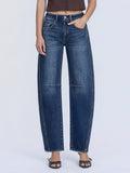 Person wearing dark blue barrel jeans on a white background