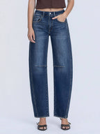 Person wearing dark blue barrel jeans on a white background